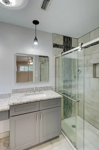 a bathroom with a granite countertop sink a mirror and shower