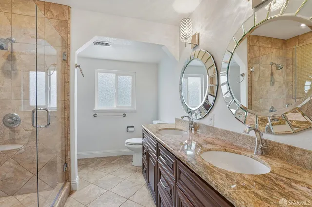 a bathroom with a granite countertop double vanity and a mirror