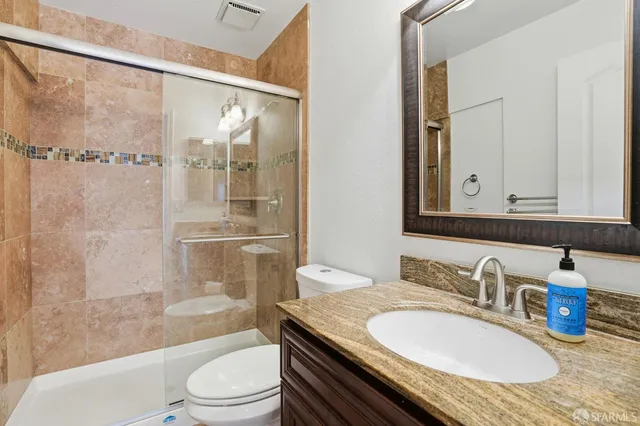 a bathroom with a granite countertop sink a toilet a mirror and shower