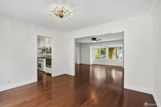 a view of an empty room with window and wooden floor