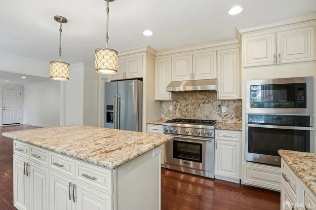 a kitchen with stainless steel appliances granite countertop a stove a refrigerator and a wooden floors