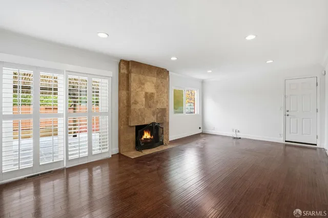 an empty room with wooden floor fireplace and windows