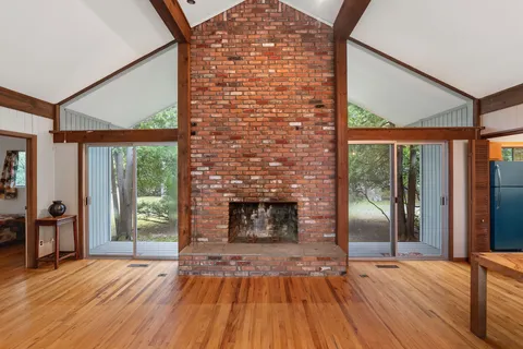 an empty room with wooden floor and a fireplace