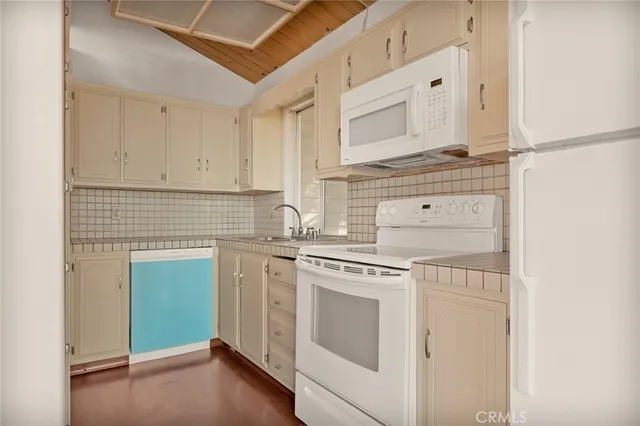 a kitchen with granite countertop white cabinets and white appliances