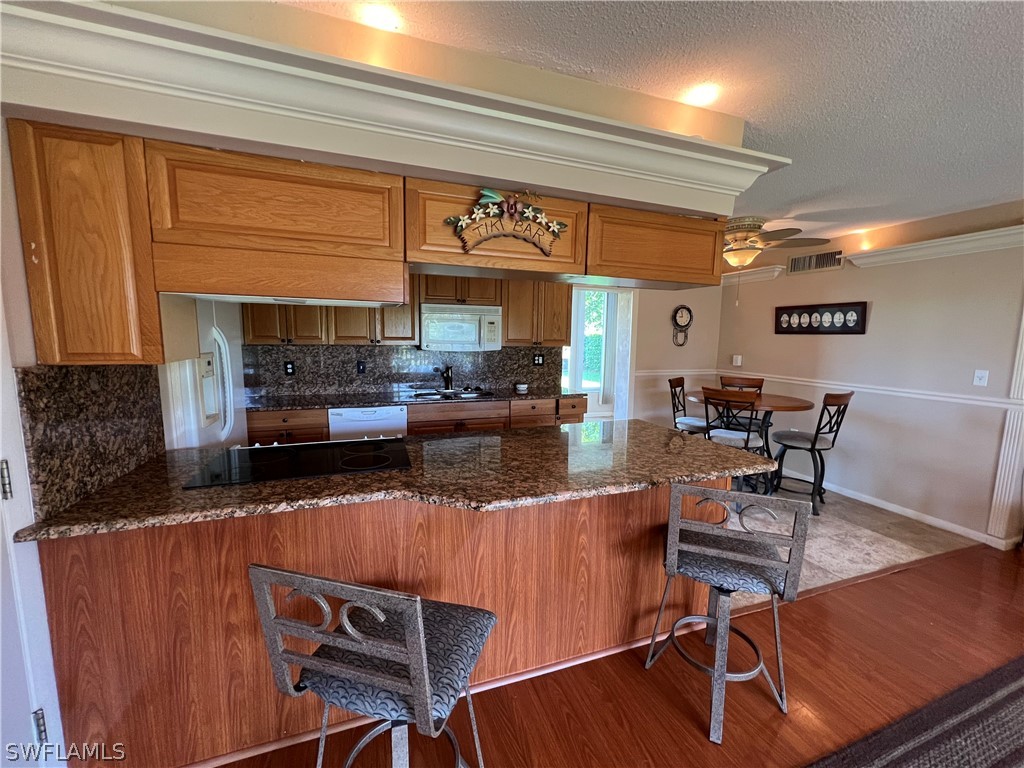 1372 Archer Street, Unit 4 Lehigh Acres, FL 33936 - Photo 10 of 22 a kitchen with stainless steel appliances granite countertop a table chairs in it and wooden floors
