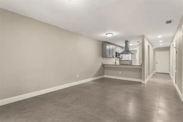 a view of kitchen and empty room with wooden floor