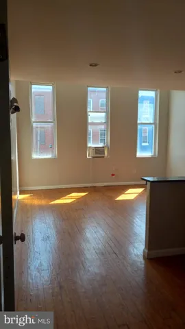 a view of an empty room with window and wooden floor