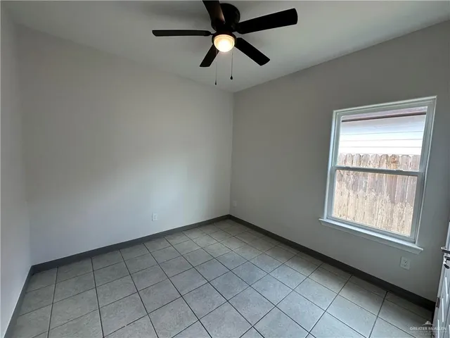an empty room with chandelier fan and windows