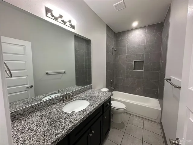 a bathroom with a granite countertop sink a toilet and shower