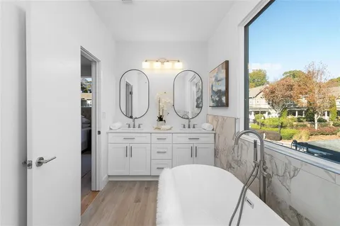 a room with mirror a sink and a wooden floor