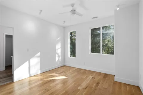 a view of an empty room with window and wooden floor