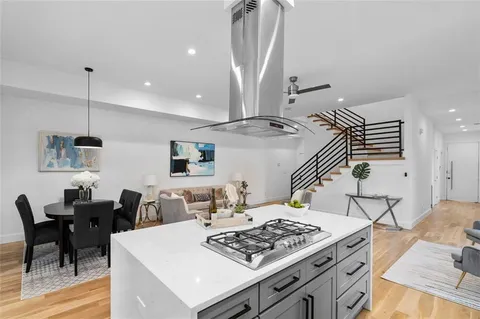 a view of kitchen island with stainless steel appliances stove a dining table and chairs with wooden floor