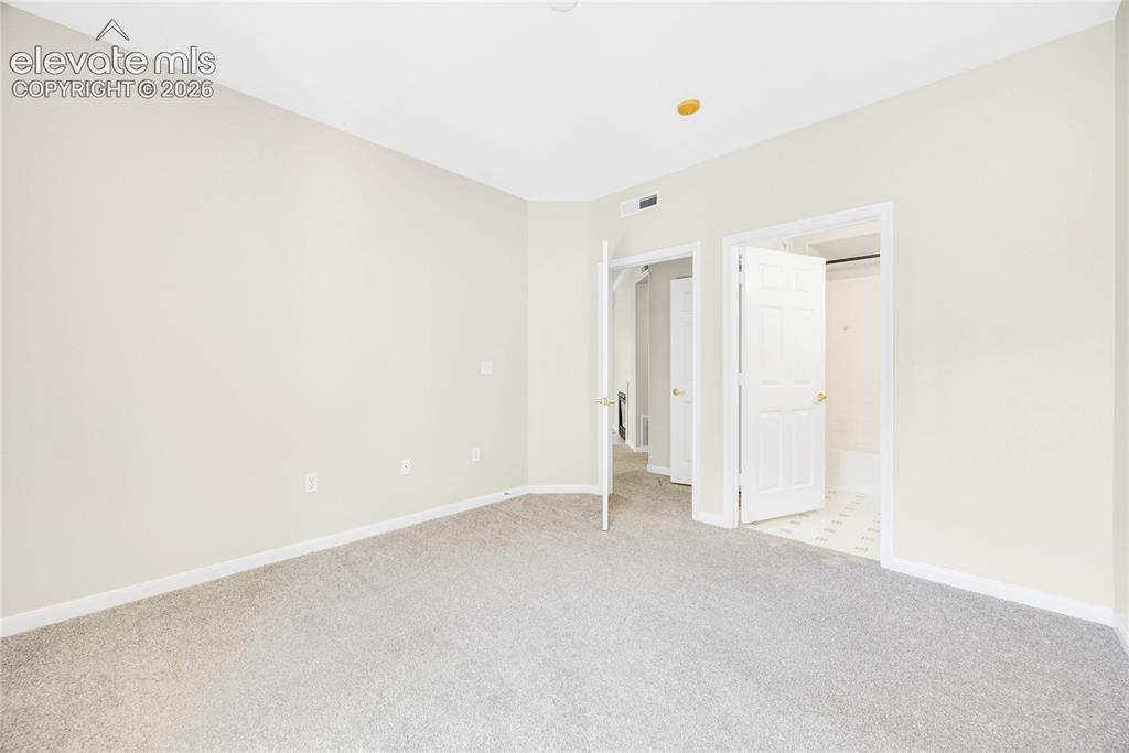 3864 Riviera Grove, Unit 102 Colorado Springs, CO 80922 - Photo 14 of 24 Carpeted room featuring light-toned walls and trim, with multiple interior door openings