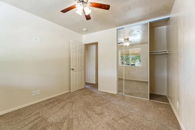 an empty room with closet and a ceiling fan