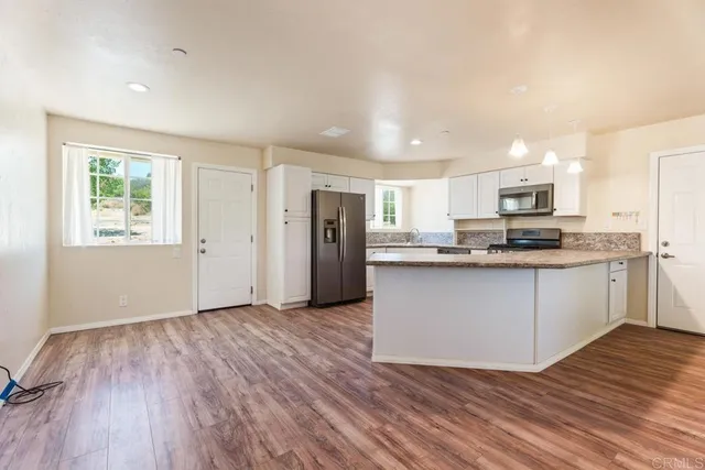 a kitchen with granite countertop wooden floors stainless steel appliances and window
