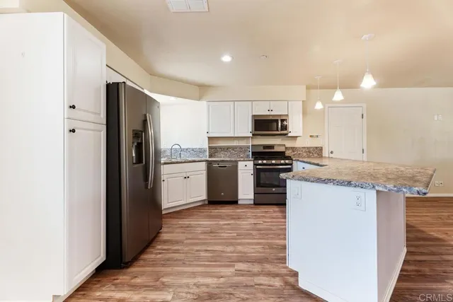 a kitchen with granite countertop a refrigerator and a stove top oven