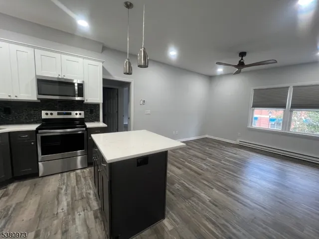 a kitchen with stainless steel appliances a stove a refrigerator a microwave oven a sink with wooden floor and cabinets