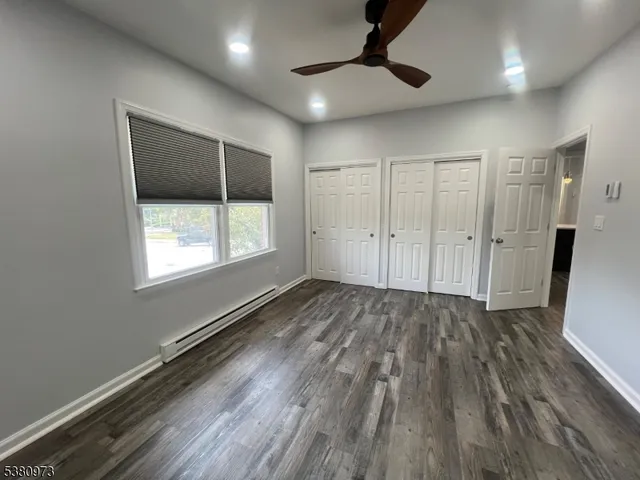 an empty room with wooden floor cabinet and windows