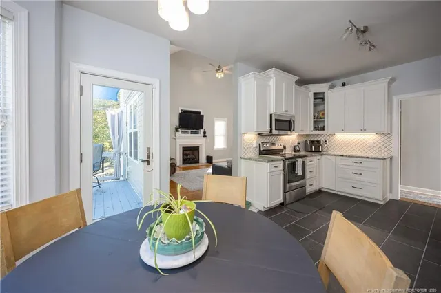a kitchen with stainless steel appliances kitchen island granite countertop a refrigerator a stove a sink dishwasher and white cabinets with wooden floor