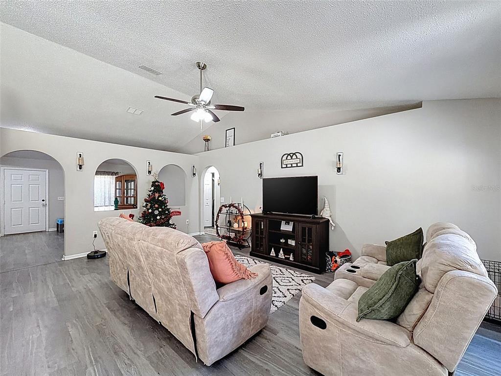 16061 Cave Swallow Road Brooksville, FL 34614 - Photo 16 of 47 a living room with furniture a ceiling fan and a flat screen tv