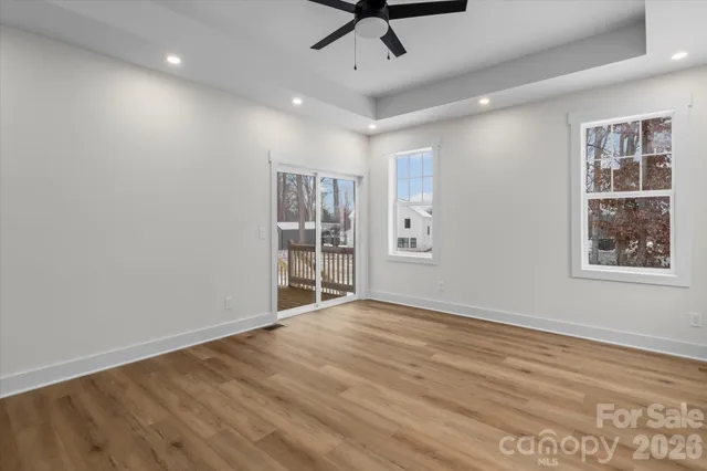 a view of empty room with wooden floor and fan