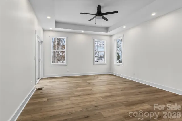 an empty room with wooden floor and ceiling fan