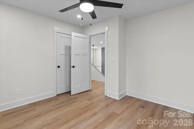 an empty room with wooden floor fan and windows