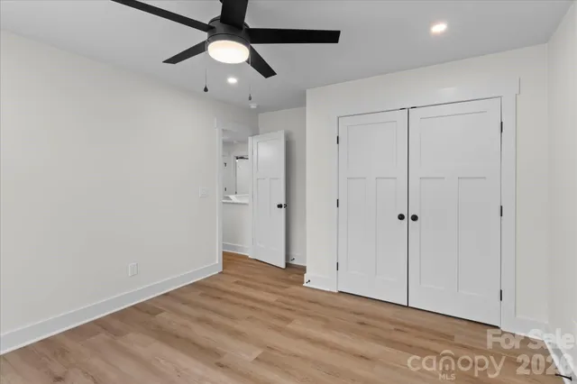 an empty room with wooden floor ceiling fan and windows