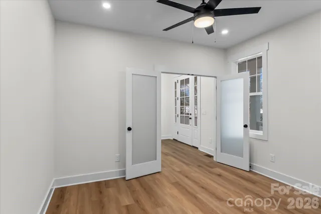 an empty room with wooden floor fan and windows