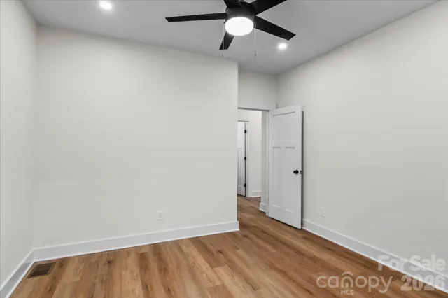 a view of empty room with wooden floor and fan