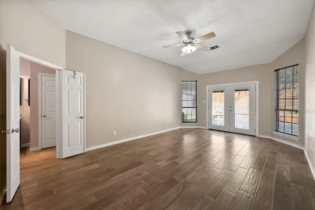 a view of an empty room with wooden floor and window