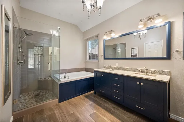 a bathroom with a sink double vanity granite tub shower and a mirror