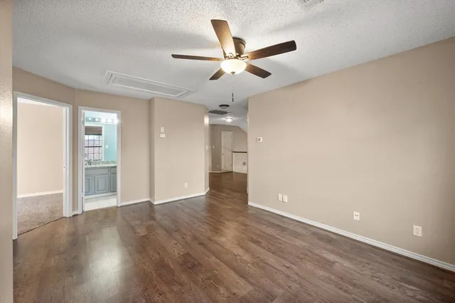 an empty room with wooden floor ceiling fan and windows