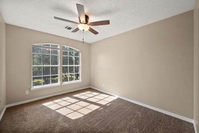 an empty room with windows and fan