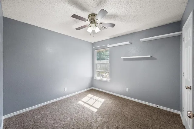 an empty room with windows and fan