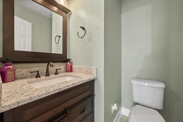 a bathroom with a granite countertop toilet sink and mirror