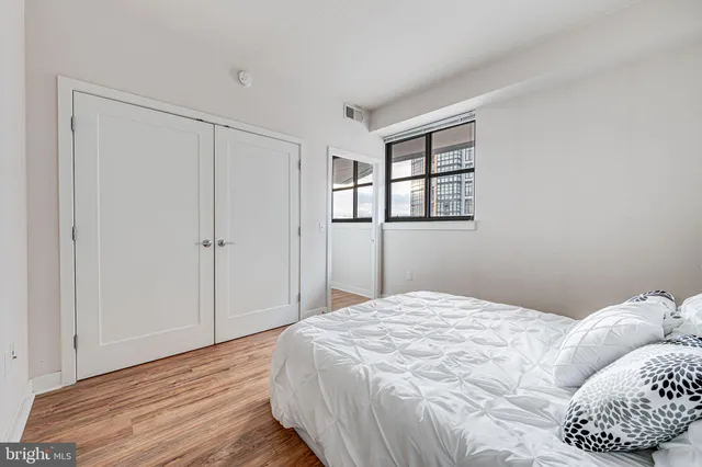 a bed sitting in a bedroom next to a window with a large bed and a wooden floor