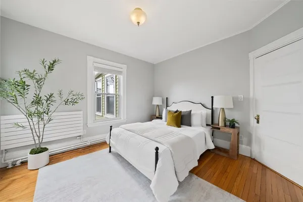 a bedroom with a bed and potted plant with wooden floor