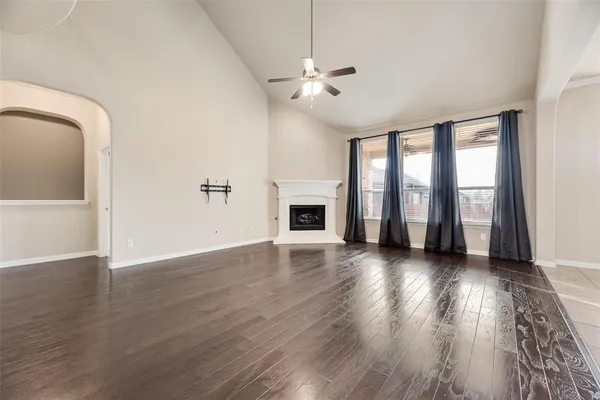 an empty room with wooden floor fireplace and windows