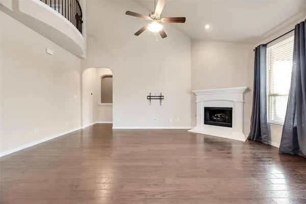 a view of an empty room with wooden floor fireplace and a window