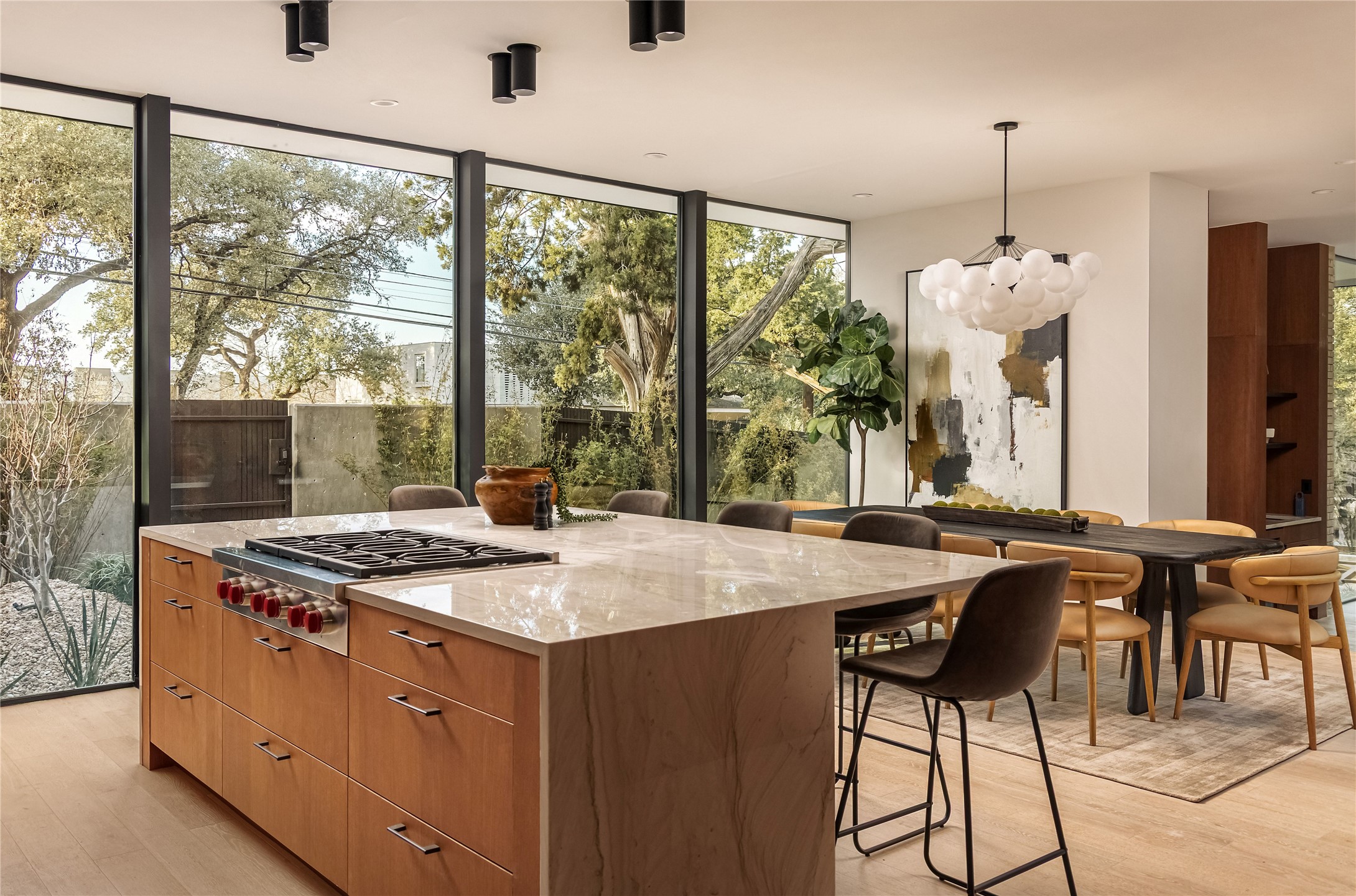 915 Columbus Street Austin, TX 78704 - Photo 13 of 34 Kitchen with a wall of windows, a kitchen breakfast bar, brown cabinetry, light stone counters, and modern cabinets