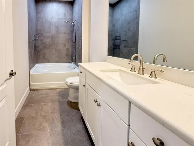 a bathroom with a granite countertop sink a toilet and bathtub