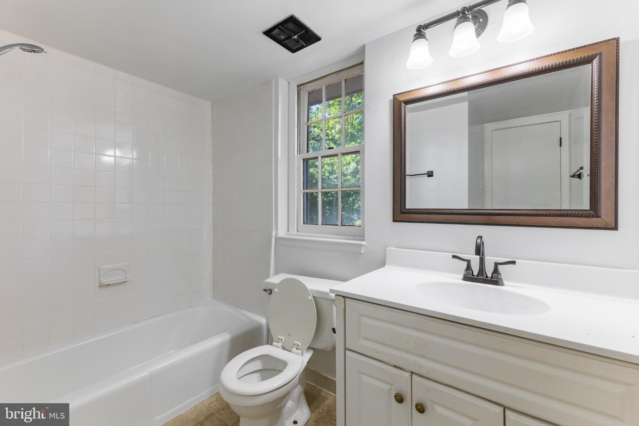 776 Quince Orchard Boulevard, Unit 102 Gaithersburg, MD 20878 - Photo 12 of 14 a bathroom with a toilet a sink a mirror and a bathtub