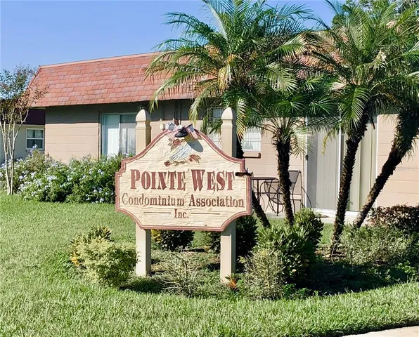 a view of a brick house with a small yard plants and palm trees