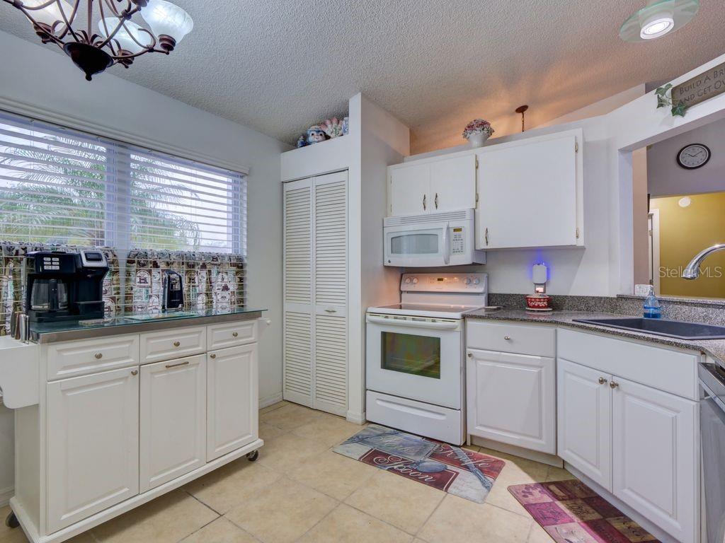 698 Colchester Avenue Deltona, FL 32738 - Photo 10 of 30 a kitchen with kitchen island granite countertop a sink and white cabinets