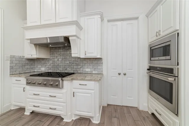 a kitchen with granite countertop white cabinets stainless steel appliances and wooden floor