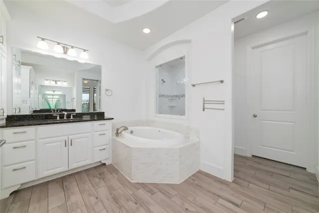 a spacious bathroom with a tub sink and mirror