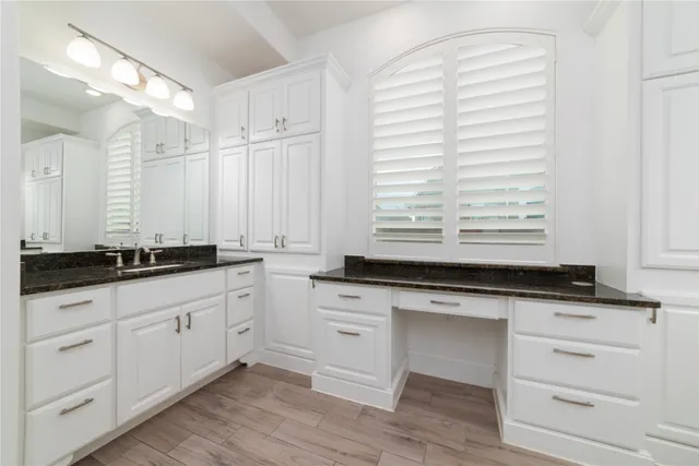 a bathroom with granite countertop white cabinets and a sink