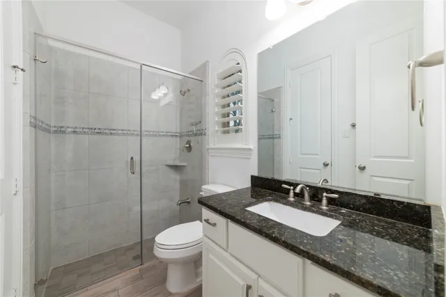 a bathroom with a granite countertop sink toilet and shower