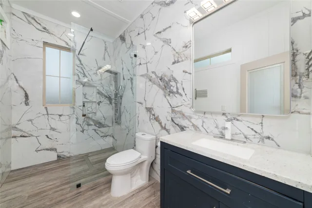 a bathroom with a granite countertop sink toilet a mirror and shower